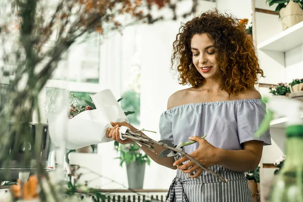 Young curly student feeling good while working in flowershop — Stock Photo, Image