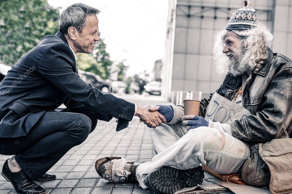 Curious short-haired businessman sitting in front of long-haired homeless