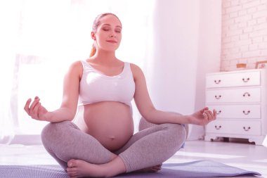 Genç ışınlama uzun saçlı hamile kadın beyaz bir t-shirt huzurlu arıyorsunuz