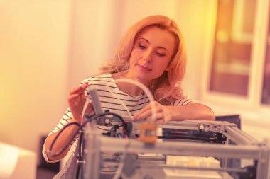 Güzel kadın bir 3d printerlere harcama maddeler bileşenleri kontrol odaklı.
