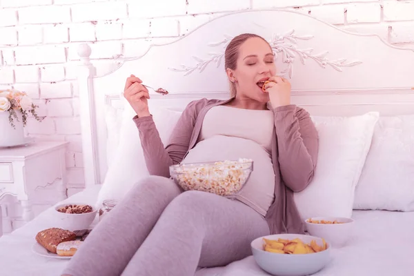 Světlovlasý hezká těhotná žena v pohodlném oblečení, jíst s radostí — Stock fotografie