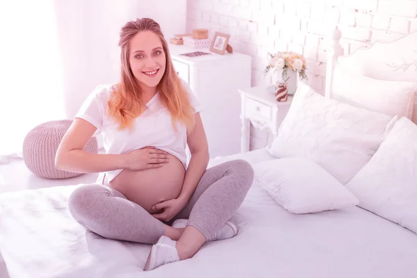 Young long-haired pregnant woman in a white t-shirt feeling good — Stock Photo, Image