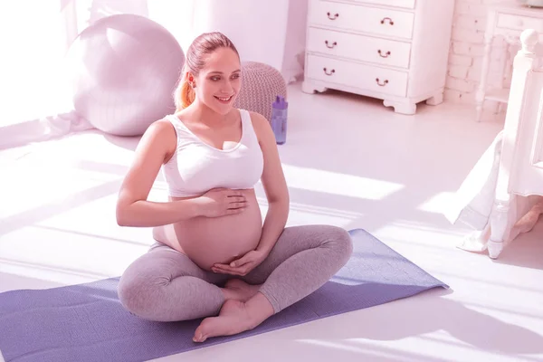 Молодая сияющая длинноволосая беременная женщина в белой футболке с животом — стоковое фото