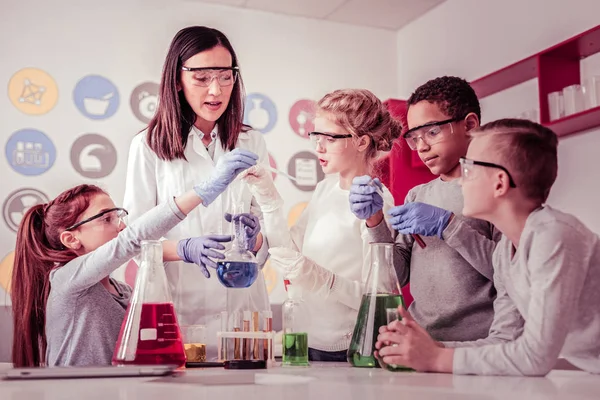 Jóvenes científicos ayudando a su profesor con reactivos — Foto de Stock