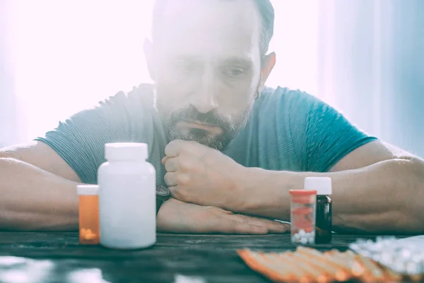 Hombre molesto angustiado tomando diferentes tipos de pastillas —  Fotos de Stock
