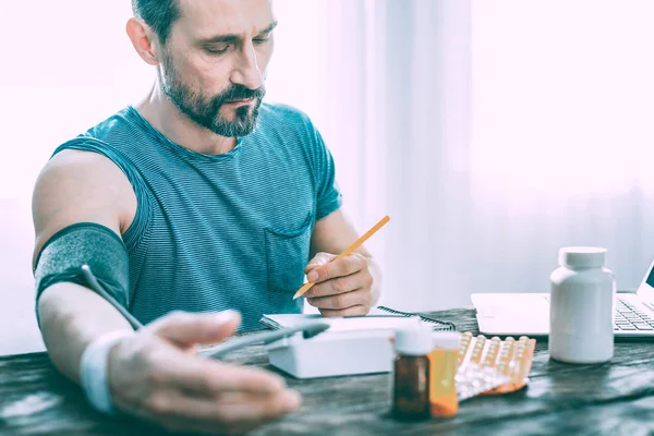 Triste chateado homem fazendo anotações sobre pílulas prescritas — Fotografia de Stock