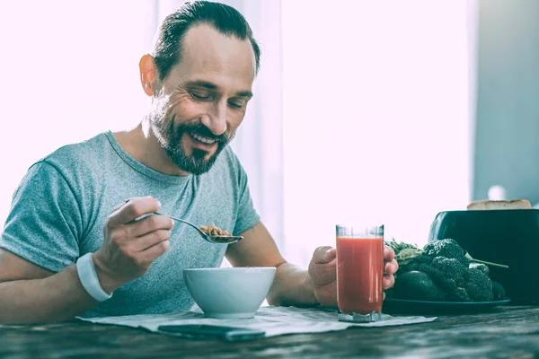 Vrolijke aardige man thuis lekker ontbijten — Stockfoto