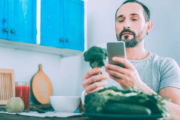 Hombre agradable concentrado sosteniendo una verdura en la mano —  Fotos de Stock