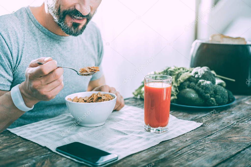 Pleasant nice man having breakfast at home
