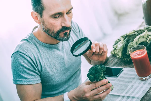 Paciente hombre tranquilo estudiando diferentes verduras verdes — Foto de Stock