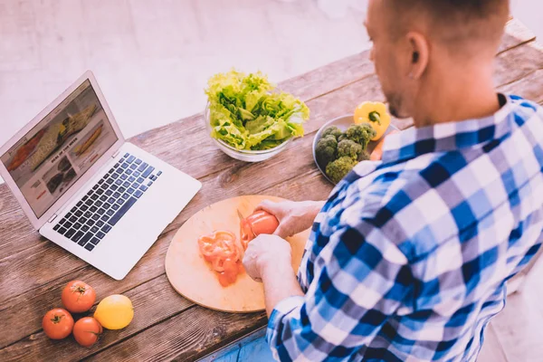 Homem atraente moderno assistindo a um vídeo tutorial na cozinha — Fotografia de Stock