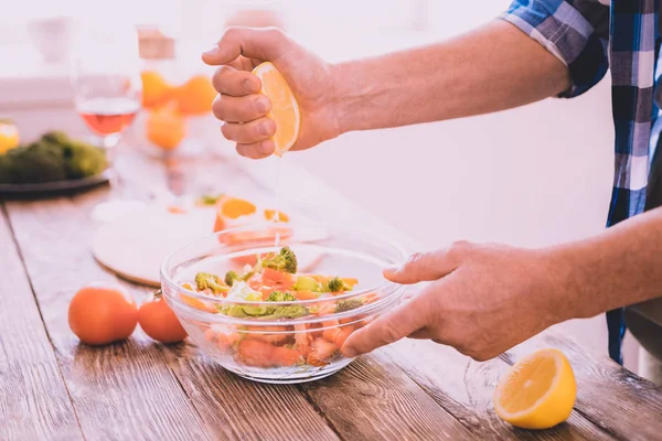 Cuisinier expérimenté ajoutant du jus de citron à un plat — Photo