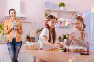 Tablo üzerinde yumurta koyarak memnun uzun saçlı çocuk bitmiş