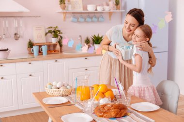 Genç annesi kucaklayan neşeli sarışın kız
