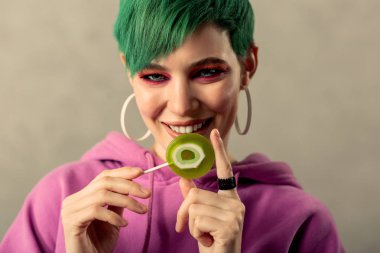 Yeşil bir lolipop gösterilen güzel pozitif kadın