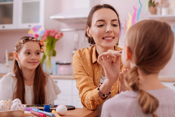 Pleased young mother doing makeup for her kid — Stock Photo, Image