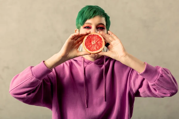 Позитивна радісна жінка тримає грейпфрут наполовину — стокове фото