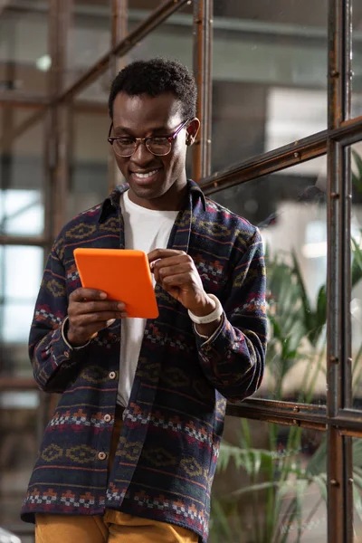 Homem sorridente usando um tablet em um caso brilhante — Fotografia de Stock