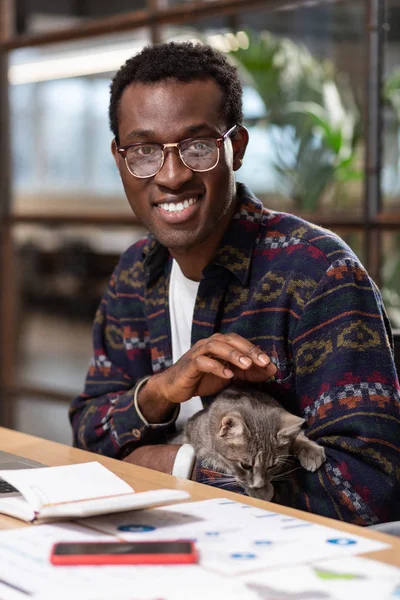 Hombre sosteniendo un gato en su lugar de trabajo — Foto de Stock