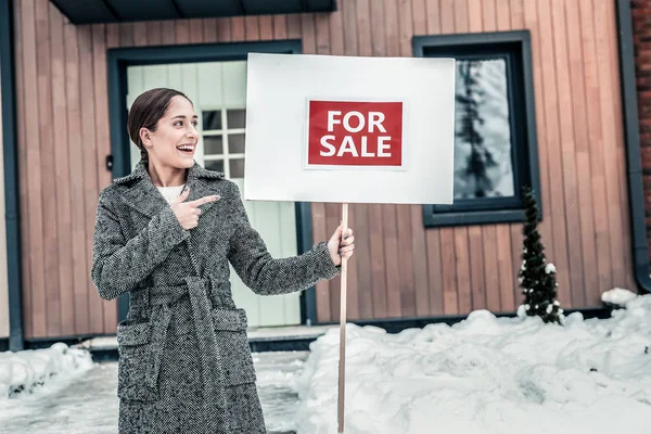 Jovem mulher atraente vestindo casaco cinza quente vendendo casa — Fotografia de Stock