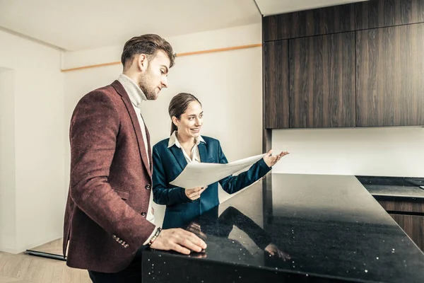 Lachende aangename makelaar tonen haar cliënt de keuken — Stockfoto