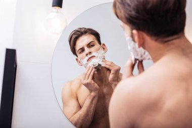 Kara gözlü yakışıklı tıraş köpüğü kullanarak hiçbir gömlek giymiş