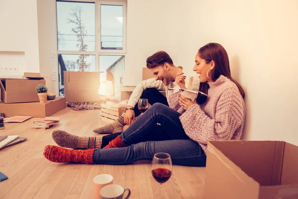 Couple laughing while eating takeaway noodles and drinking wine — Stock Photo, Image