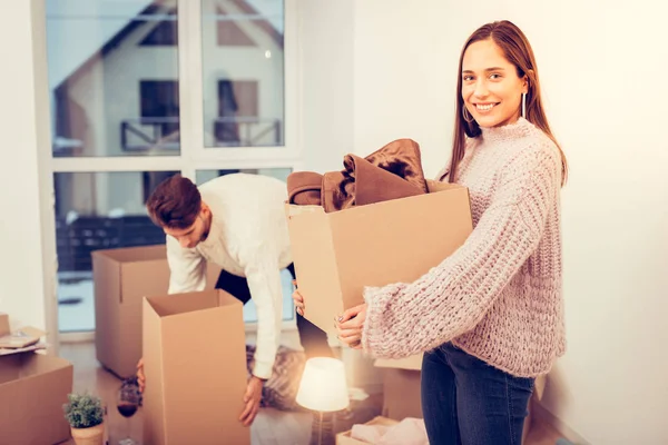 Fru bär varm tröja hålla låda medan du flyttar i nya hus — Stockfoto