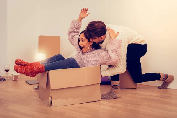 Funny happy wife sitting in empty box after unpacking clothes