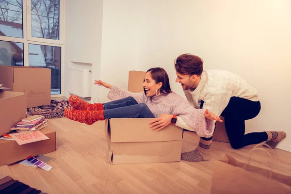 Wife wearing warm red socks sitting in empty box near her husband — Stock Photo, Image