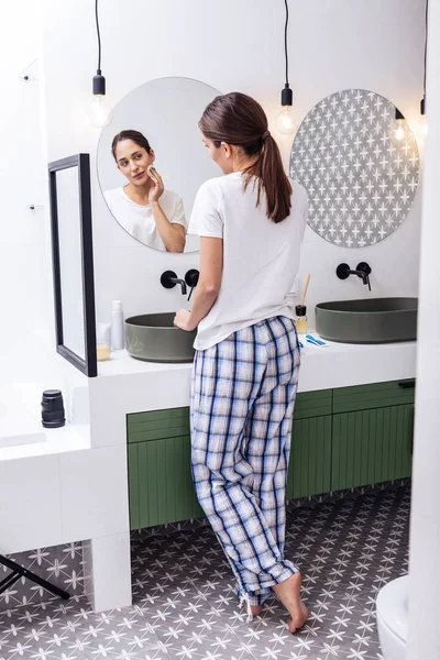 Mulher de cabelos escuros usando calças de pijama quadradas removendo maquiagem — Fotografia de Stock