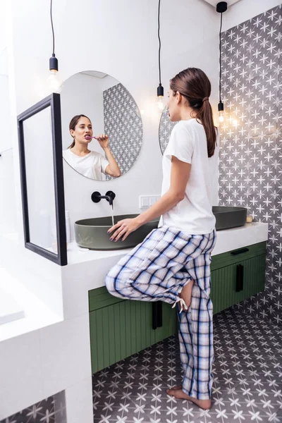 Tmavovlasá žena čištění zubů v její světlé moderní koupelně — Stock fotografie