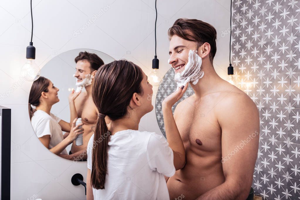 Husband with nice sexy abs hugging wife putting shaving foam