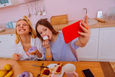 Kız kardeş eğleniyor krem burun üzerinde koyarak ve komik fotoğraflar yapmak