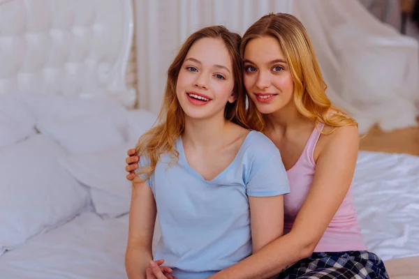 Uyanma sonra yatağın üstüne oturan pijama giymiş iki kız kardeş — Stok fotoğraf