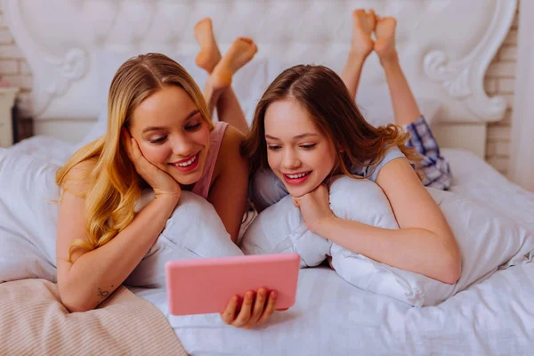Сестры в пижаме отдыхают в постели и смотрят кино. — стоковое фото