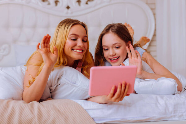 Daughters waving their hands while having video chat with parents