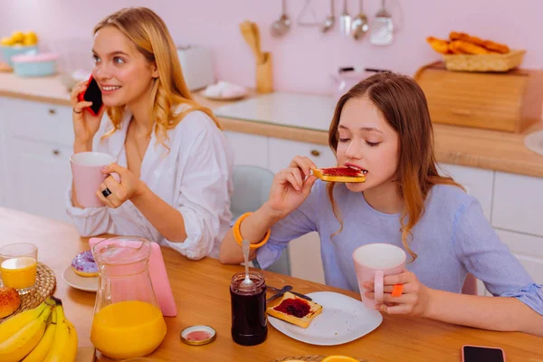 Tienermeisje eten toast met jam terwijl oudere zus spreken — Stockfoto