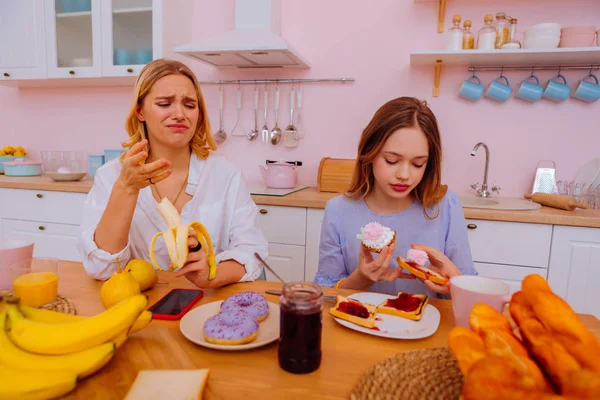 Hermana teniendo una dieta saludable sintiéndose disfrazada mirando dulces — Foto de Stock