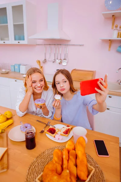 Hermanas disfrutando de un día en familia haciendo autofoto divertida durante el desayuno — Foto de Stock