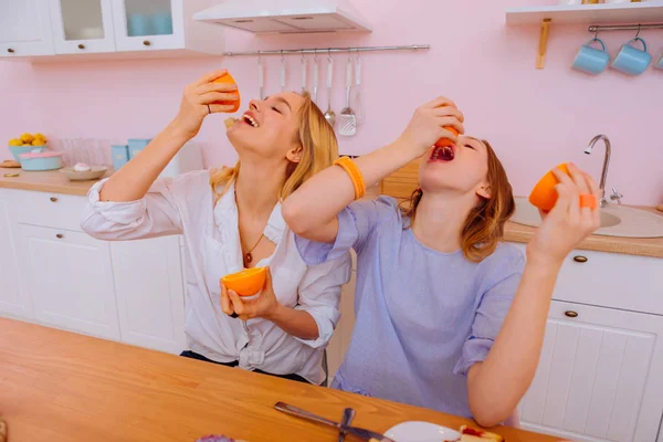 Сестры любят апельсины втискивая сок в рот — стоковое фото
