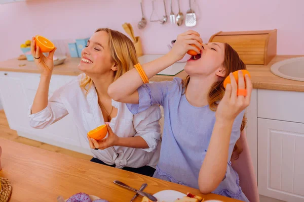 Братья и сёстры веселятся, втискивая апельсиновый сок в рот — стоковое фото