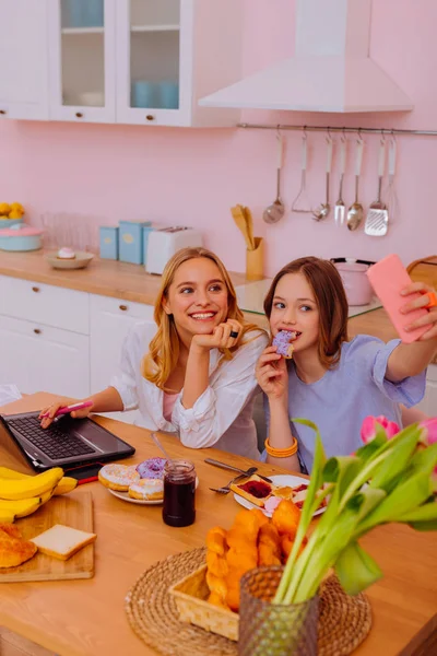 Chica sosteniendo el teléfono inteligente mientras hace selfie con su hermana mayor —  Fotos de Stock