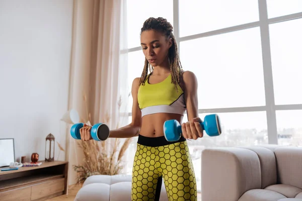 Woman wearing yellow leggings and top holding barbells