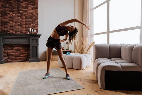 Woman stretching her body after finishing workout at home