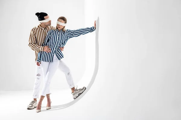 Couple wearing white trousers and striped shirts posing together — Stock Photo, Image