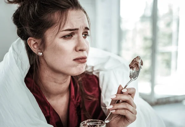 Upset woman holding a spoon of dessert — Stock Photo, Image