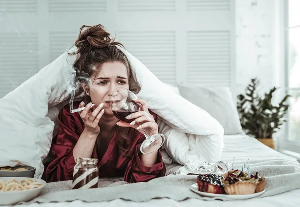 Mujer deprimida fumando en la cama y bebiendo vino — Foto de Stock