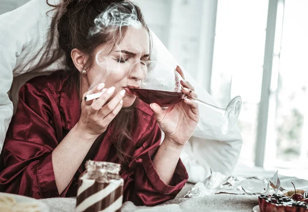 Mujer deprimida bebiendo tabaco y comiendo mucho — Foto de Stock