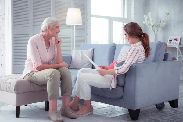 Loving mother smiling while listening to pregnant daughter — Stock Photo, Image